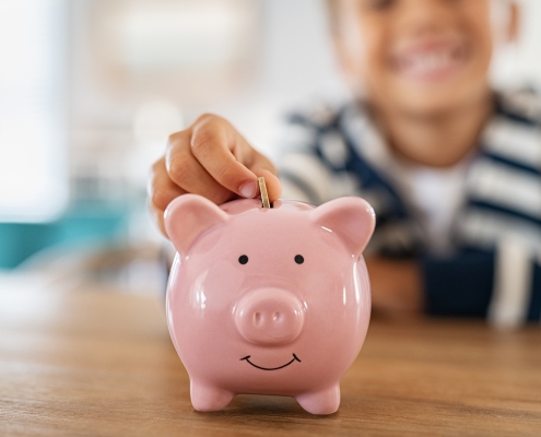 child putting coin into piggy bank